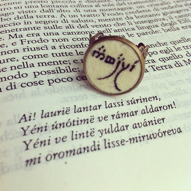 A book page and pin with Elvish language written on them